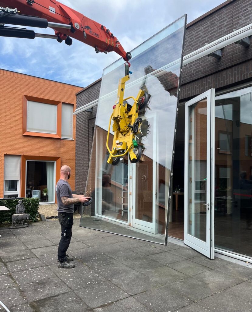 Met een grote kraan een groot glaswerk plaatsen