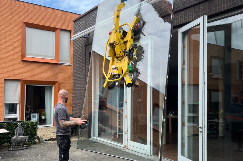 Met een grote kraan een groot glaswerk plaatsen